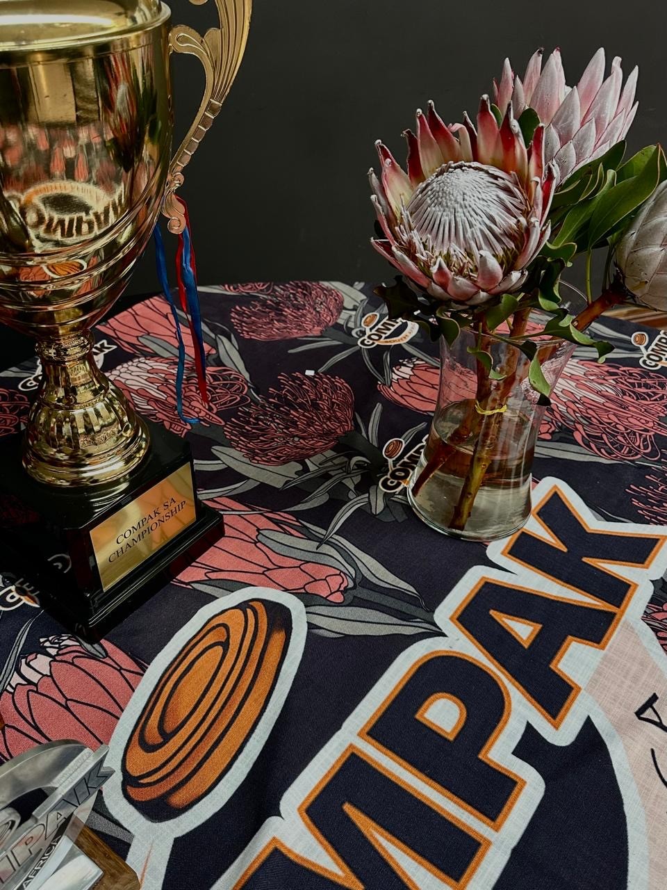 Compak SA Championship trophy with king protea flowers on a branded tablecloth