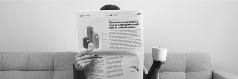 Person reading a newspaper on a sofa with a cup of coffee